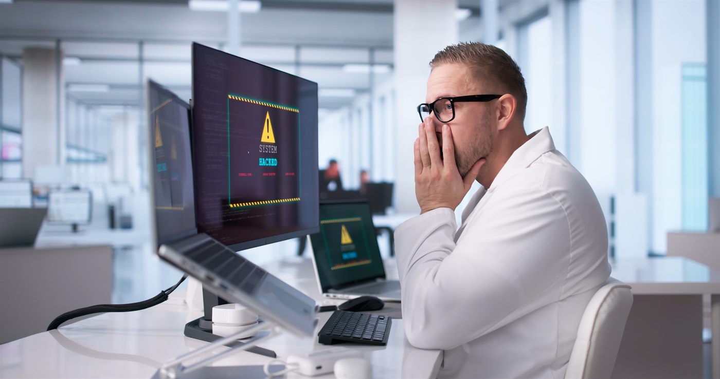 Mitarbeiter vor einem Bildschirm mit Warnmeldung nach einem Cyberangriff